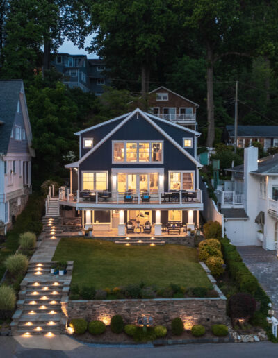 Evening aerial shot of the home illuminated with warm lights, showing waterfront access.